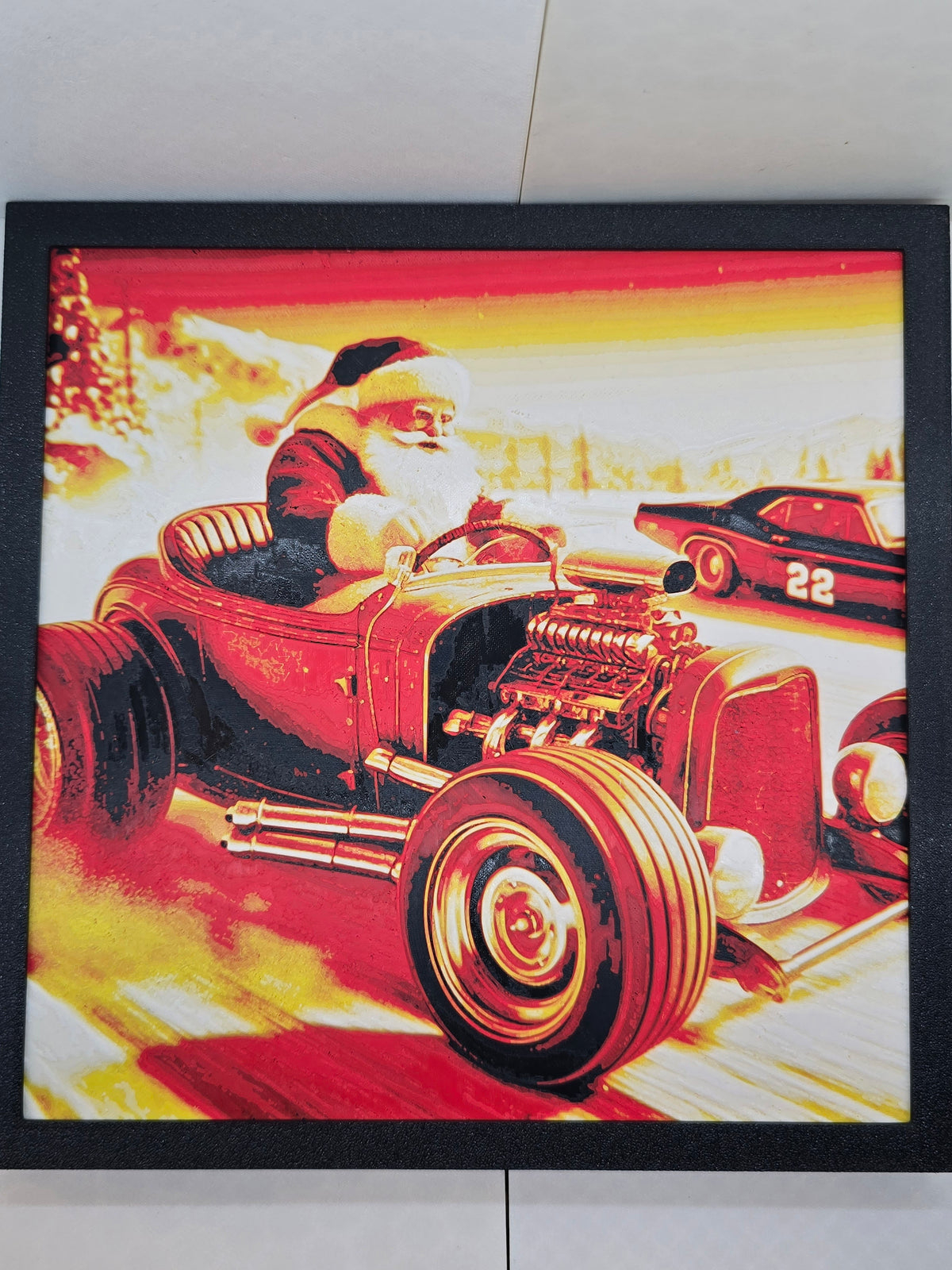 3D printed framed art of Santa Claus driving a red and yellow hotrod in a high-speed race.