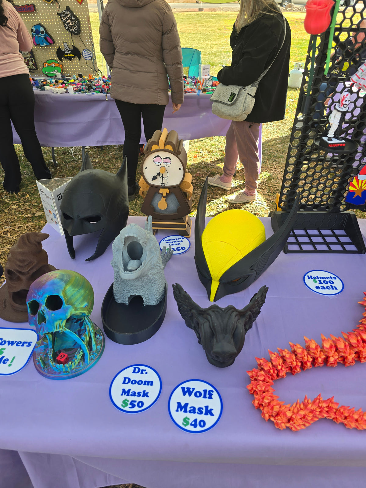 3D printed yellow and black Wolverine helmet displayed on a table at an outdoor market.