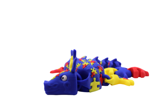 3D printed articulated autism awareness dragon in blue, red, and yellow with puzzle piece body details and tail end