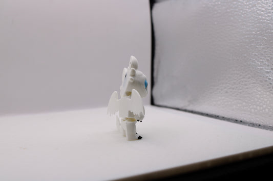 Side view of a white 3D printed Light Fury dragon with blue eyes in a white studio setting.