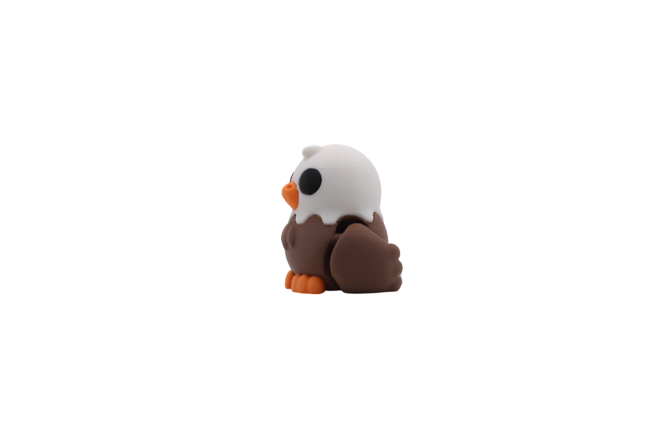 3D printed articulated bald eagle with a white head, brown body, and orange beak and feet.
