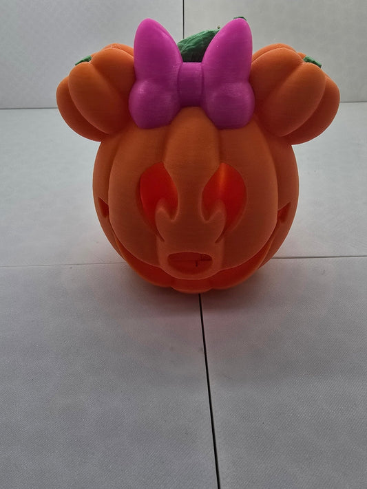 3D printed orange Minnie Mouse pumpkin tea light holder with a bright pink bow and green stem.