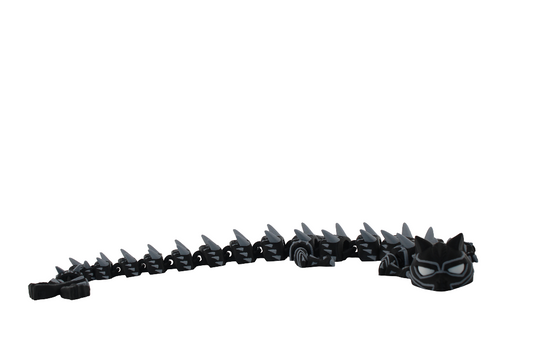 3D printed articulated Black Panther dragons in large with black bodies, white eyes, and silver back spikes