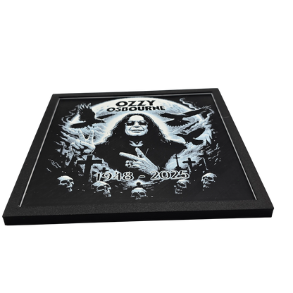 Framed memorial painting for Ozzy Osbourne with crows, skulls, and cross symbols and birth and death years on a black background.