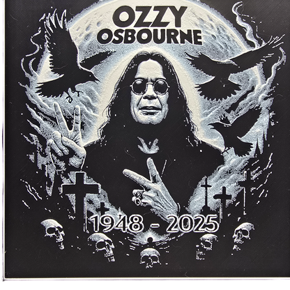 Framed memorial painting for Ozzy Osbourne with crows, skulls, and cross symbols and birth and death years on a black background.