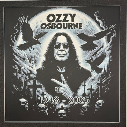 Framed memorial painting for Ozzy Osbourne with crows, skulls, and cross symbols and birth and death years on a black background.