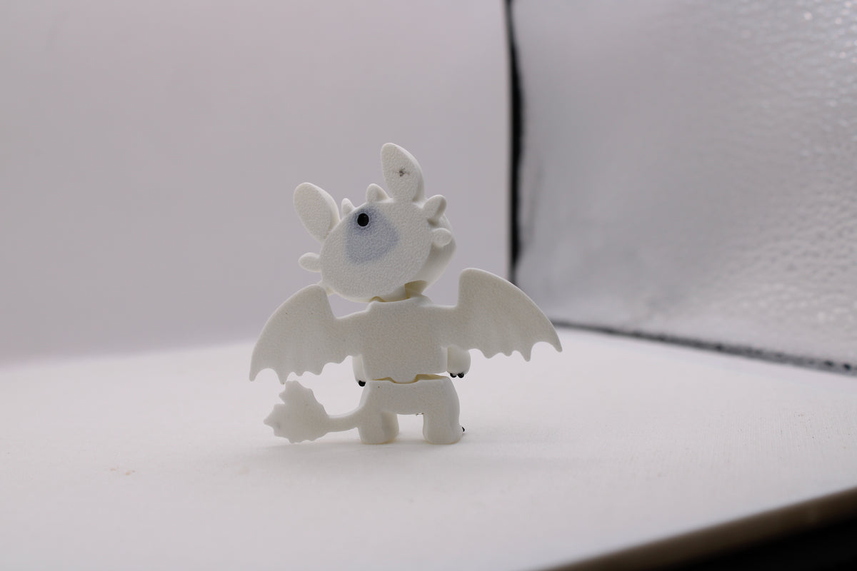 Back view of a white 3D printed Light Fury dragon with wings spread and detailed tail fins.