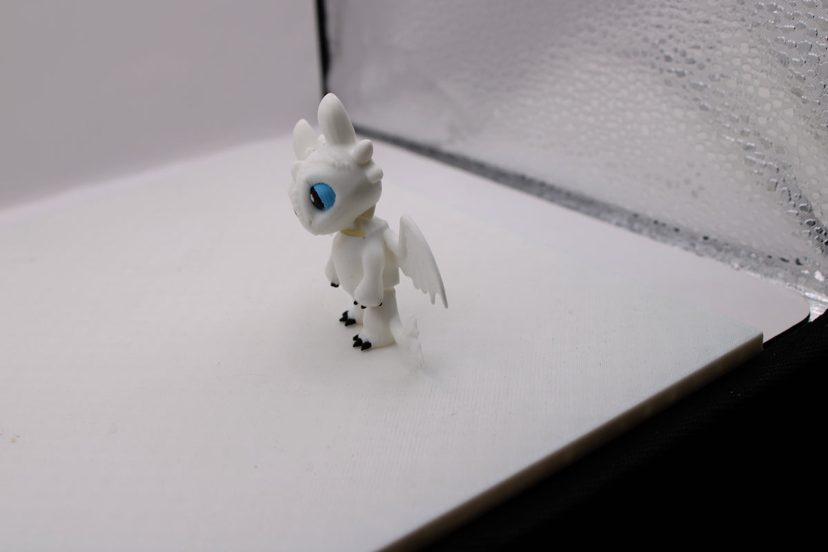 3D printed white Light Fury miniature with blue eyes in a standing pose.