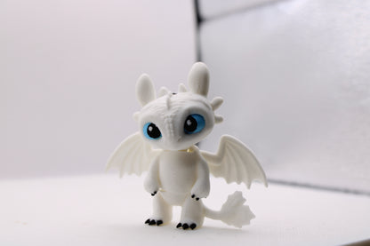 3D printed white Light Fury dragon figurine with blue eyes and black claws on a white background.