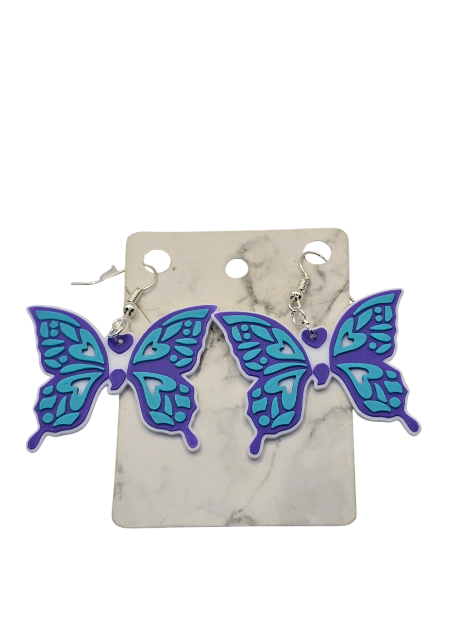 Butterfly-shaped earrings on a marble card with a white background