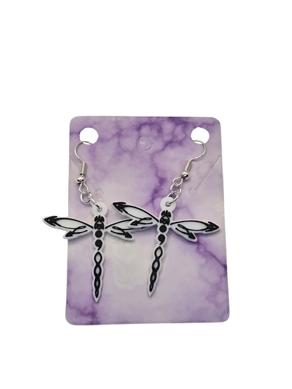 Dragonfly-shaped earrings on a purple and white marbled card