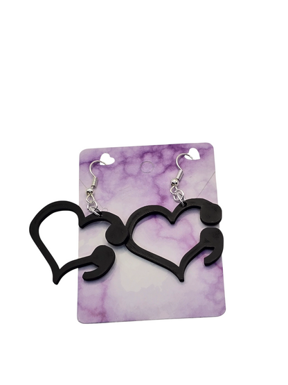 Black heart-shaped earrings on a purple and white marbled card