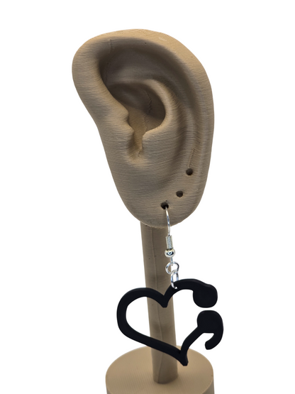 Black heart-shaped earrings on a 3d printed mannequin ear with a white background