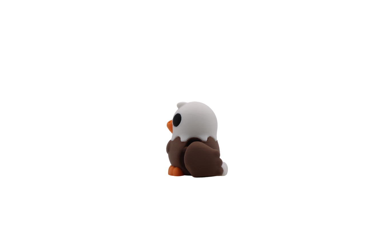 Side view of a 3D printed bald eagle flexi with a white head, brown body, and orange beak and feet.