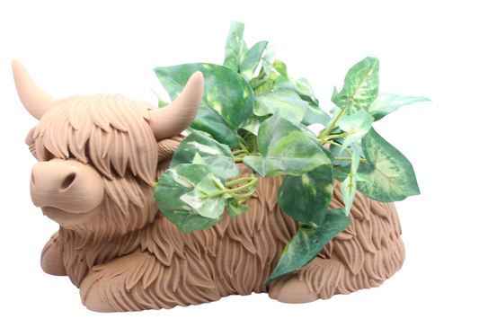 Brown highland cow shaped planter with shaggy texture and green leafy plants.