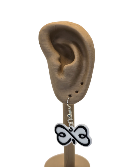 Earring with a black and white design hanging from a 3d printed ear on a white background
