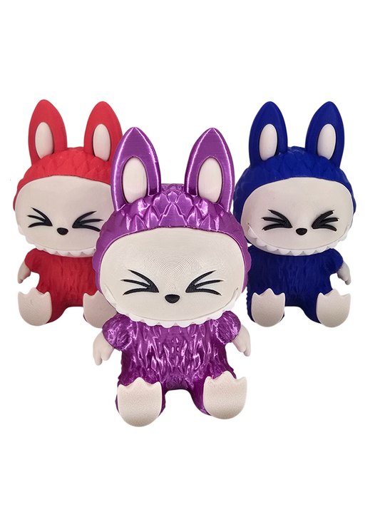 Three 3D printed Labubu figures in red, purple, and blue with pointed ears and closed eyes.