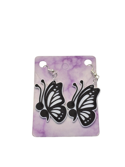 Butterfly-shaped earrings on a purple and white marbled card