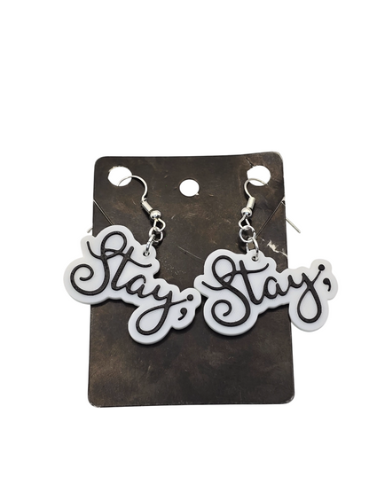Pair of 'Stay ;' earrings on a black card with a white background