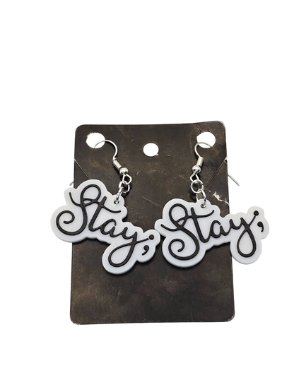 Pair of 'Stay ;' earrings on a black card with a white background
