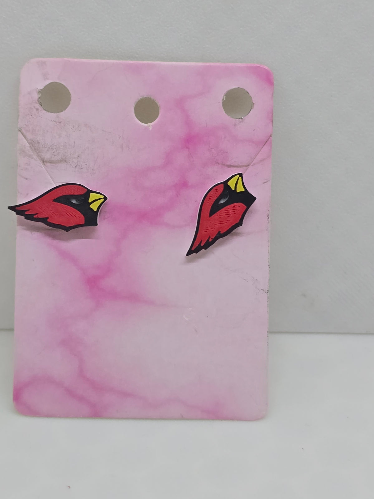 3D printed Arizona Cardinals logo stud earrings on a pink marble display card.