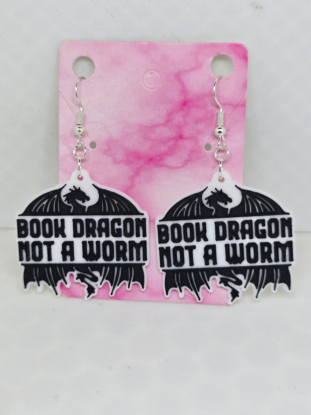 3D printed earrings featuring a black dragon silhouette and the text Book Dragon Not A Worm.