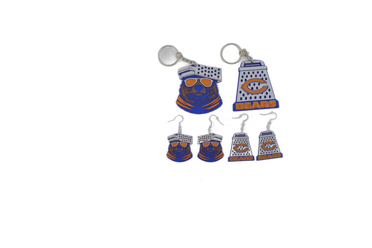 Zoomed out 3D printed Chicago Bears grouping with bear head keychain, cheese grater keychain, and four petite cheese grater earrings in blue, orange, and white.