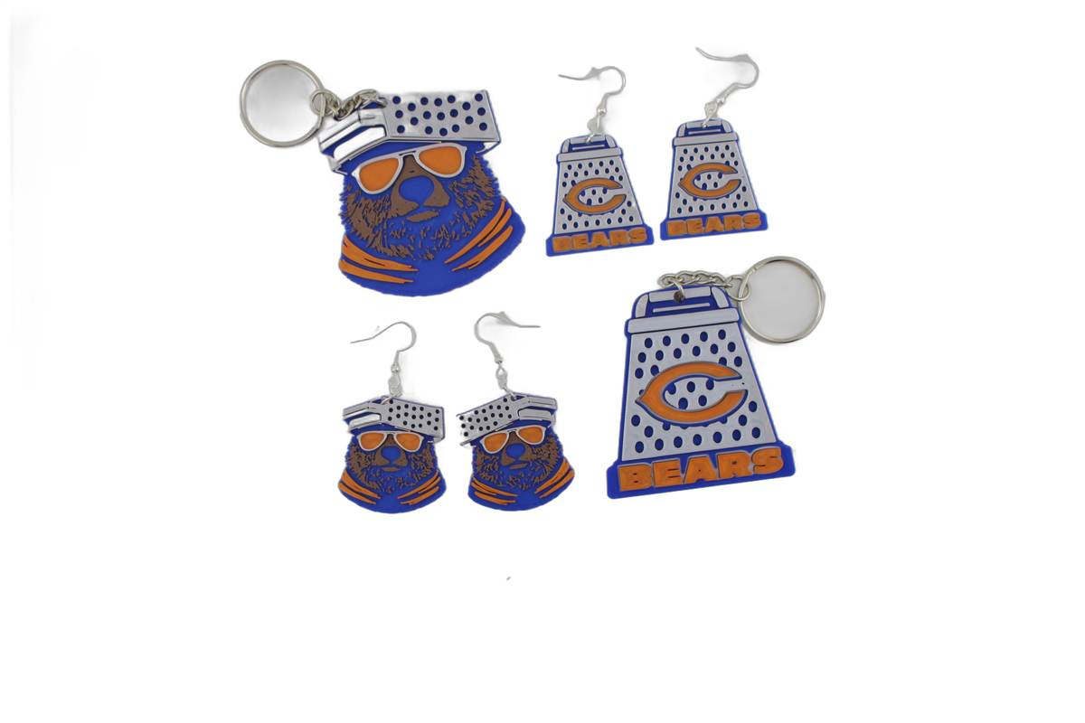 Mixed 3D printed Chicago Bears assortment — bear head keychain, cheese grater keychain, bear head earrings, and cheese grater earrings scattered together.