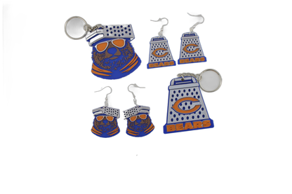 Mixed 3D printed Chicago Bears assortment — bear head keychain, cheese grater keychain, bear head earrings, and cheese grater earrings scattered together.