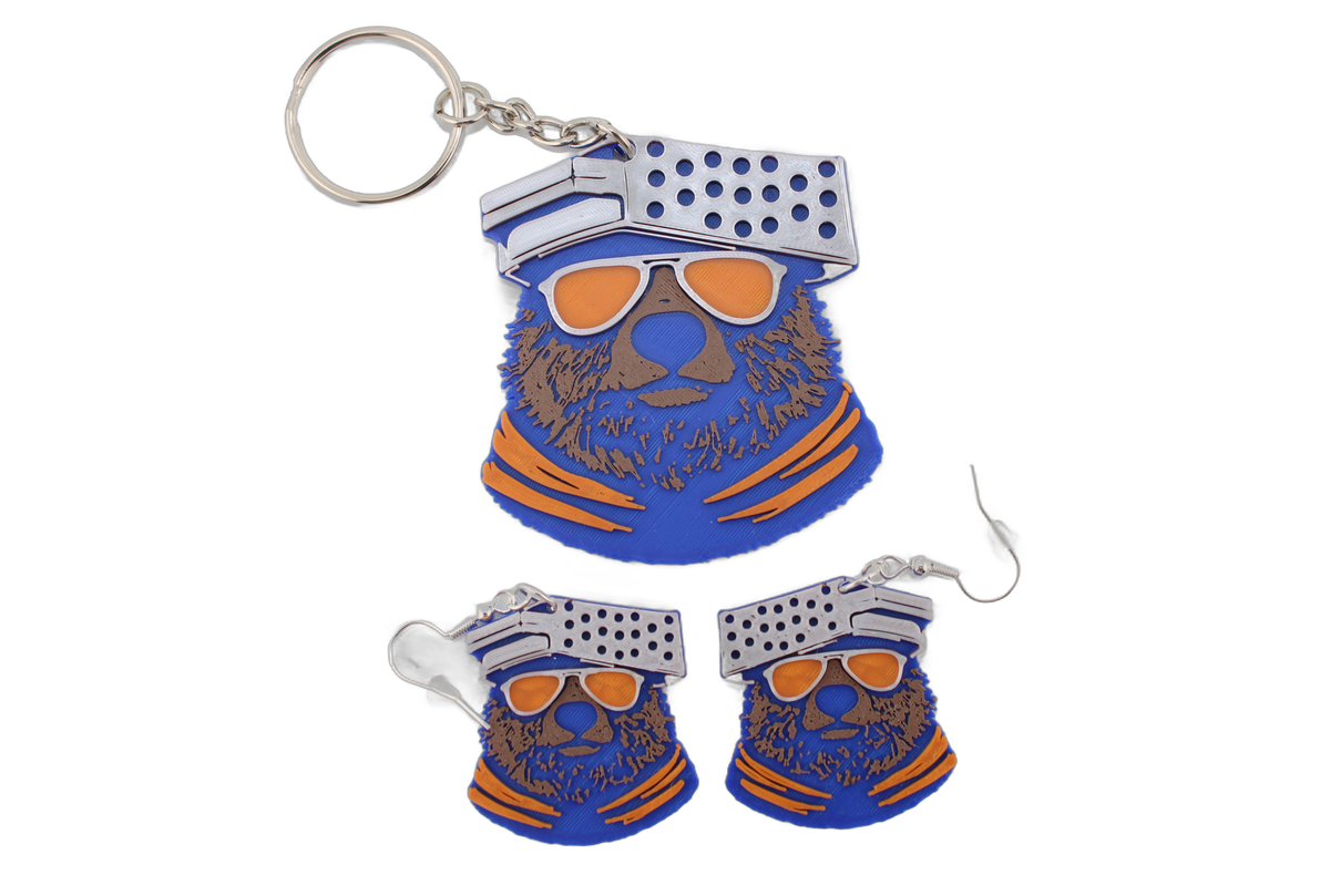 3D printed Chicago Bears bear head keychain displayed above a pair of matching bear head earrings, all in vibrant blue, orange, and white.
