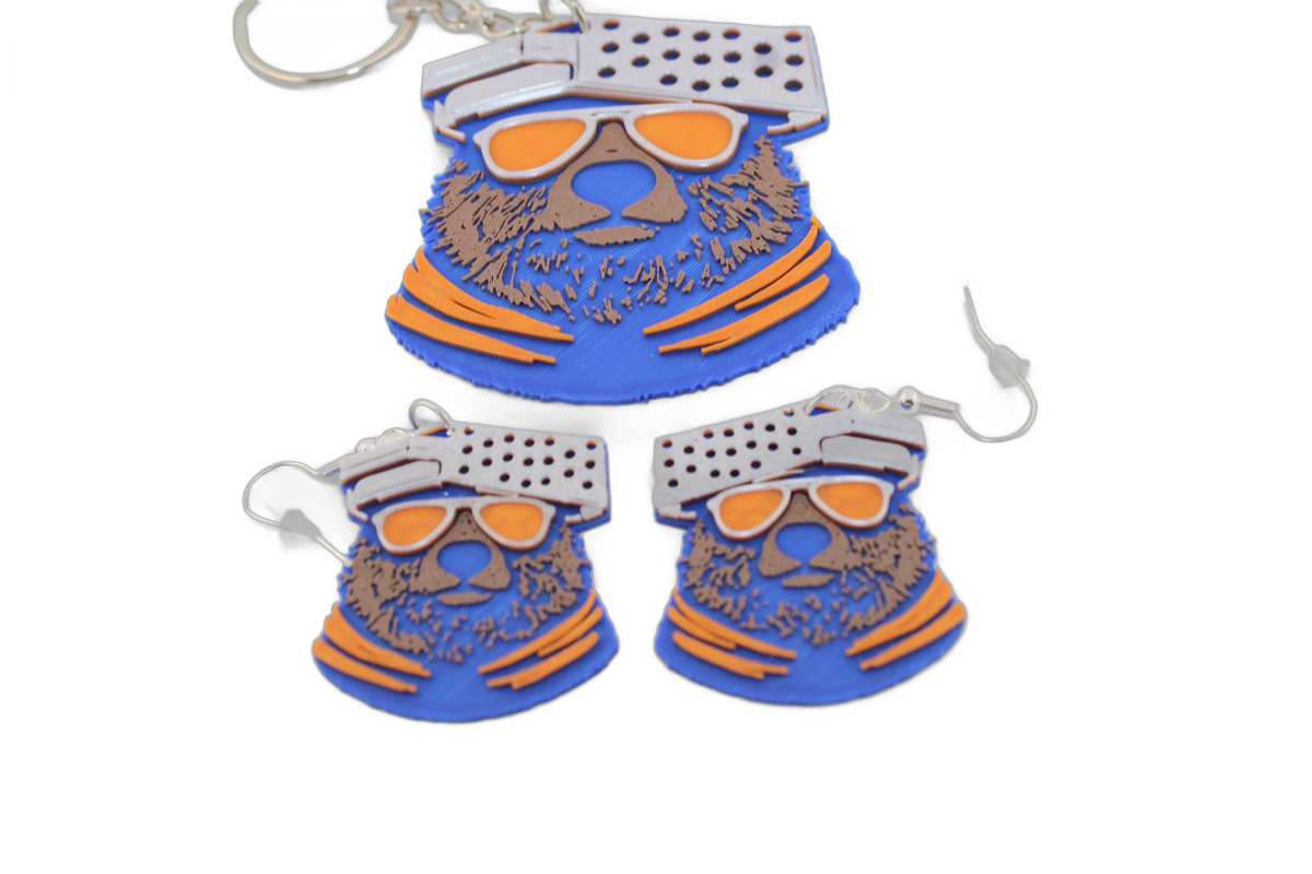 Trio of 3D printed Chicago Bears bear head pieces — one keychain and two earrings with orange sunglasses and cheese grater hats.