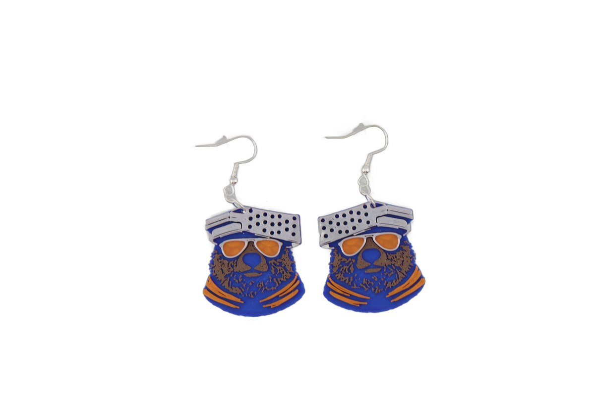 Pair of 3D printed Chicago Bears bear head earrings — blue bears with brown muzzles wearing orange sunglasses and silver cheese grater caps.