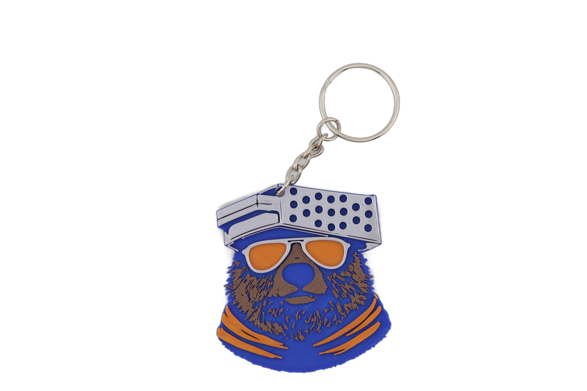 Single 3D printed Chicago Bears bear head keychain with metal ring — blue bear sporting orange sunglasses and a cheese grater cap.