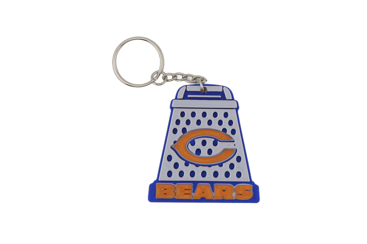 Single 3D printed Chicago Bears cheese grater keychain with metal split ring — blue and white grater with orange C logo and BEARS text.