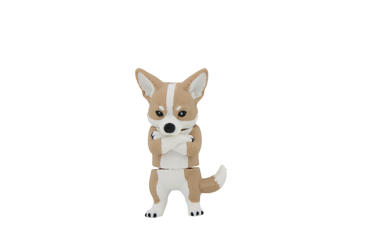 Front close-up of a tan and white 3D printed corgi figurine with black nose and paw details, standing upright with its front paws crossed — find this funny desk buddy at Erratically Eccentric Creations.