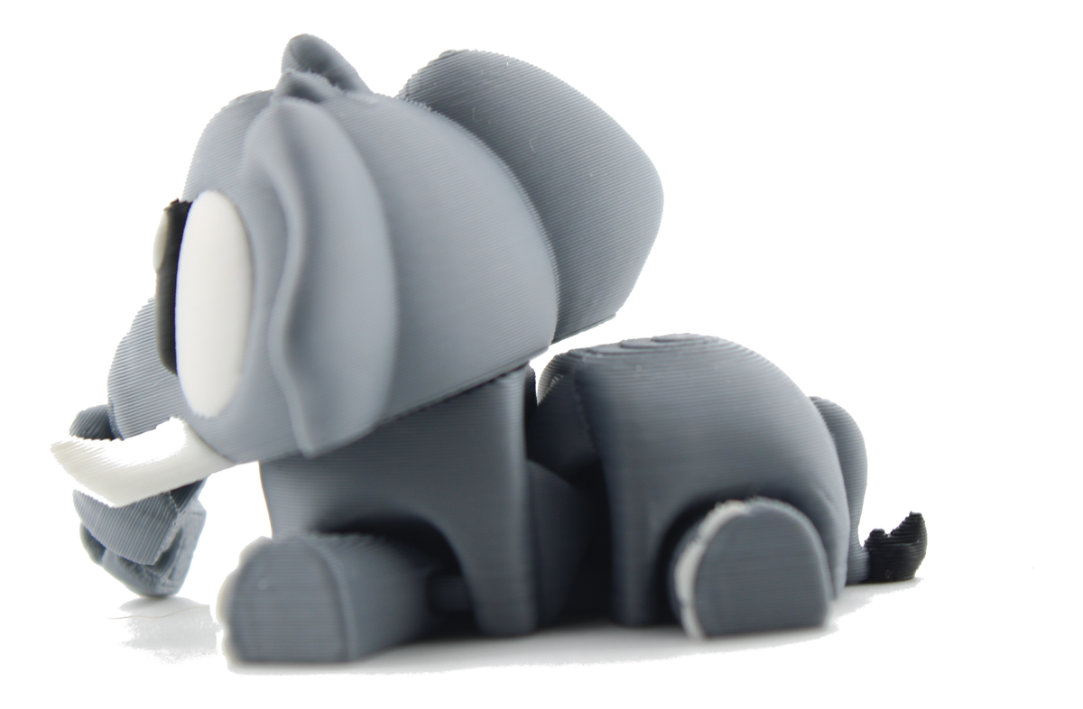 3D printed flexi elephant lying down seen from the side, gray body stretched out with its black-tipped tail behind