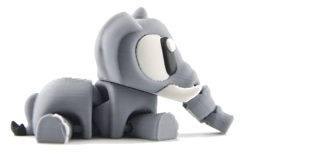 Lying-down side view of the 3D printed baby elephant facing right, gray with a white tusk and its articulated trunk extended forward