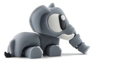 The 3D printed articulated elephant resting on its belly in profile, gray with big white eyes and trunk stretched out ahead