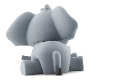 Back view of the 3D printed baby elephant lying down, gray ears spread wide and a thin tail with a black tip