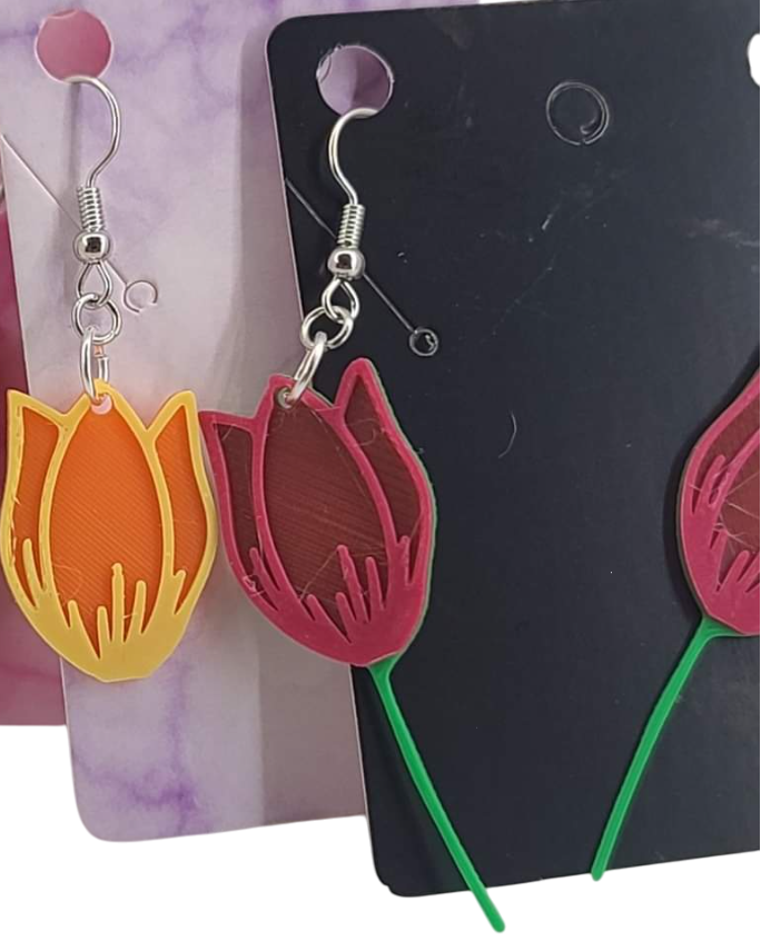 3D printed tulip earrings in orange and yellow, and dark red with green stems on silver hooks.