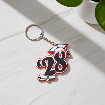 3D printed '28 graduation keychain in red, white, and black with a cap and diploma.