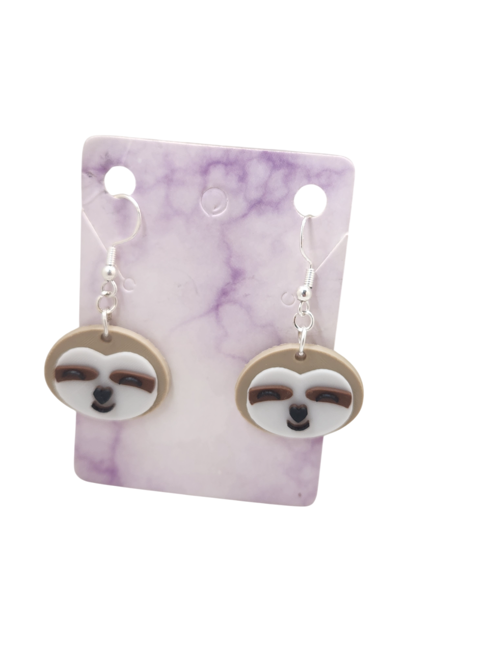 3D printed sloth face earrings with silver hooks on a purple marble display card.