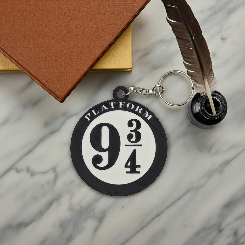 3D printed Platform 9 3/4 keychain on a marble surface with a quill, inkwell, and books.