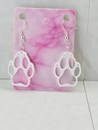 3D printed white hollow wolf paw print dangle earrings with silver-plated hooks on a pink card.